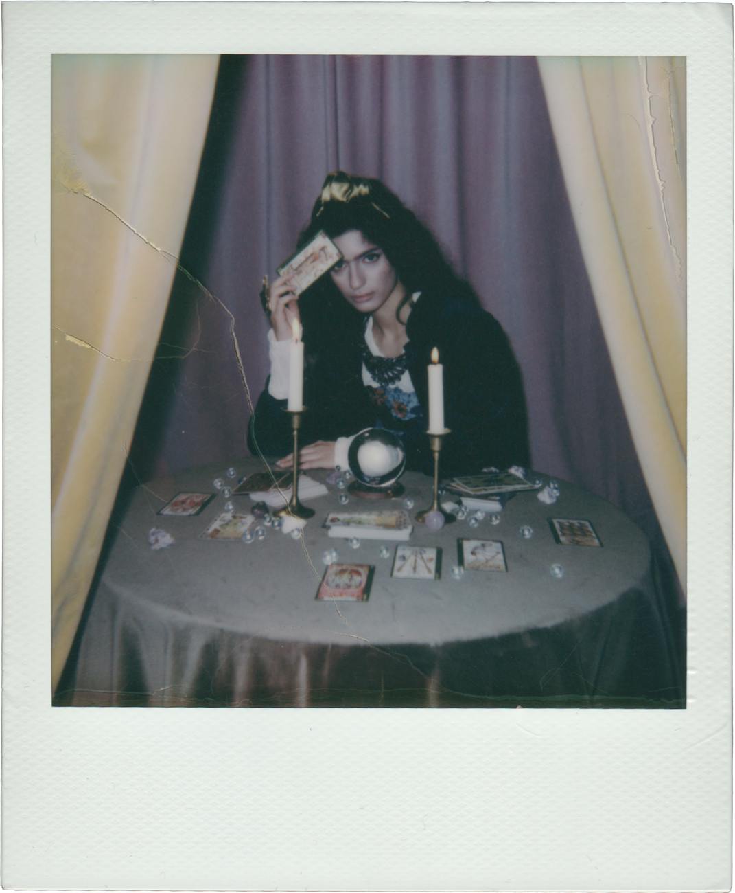 polaroid picture of a fortune teller holding a tarot card